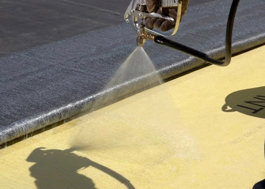 Person using a pressurised contact adhesive glue spraying concrete surface
